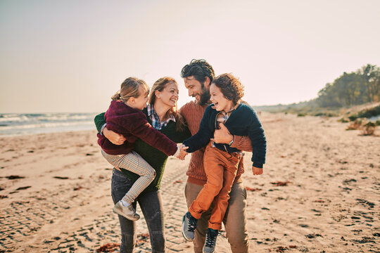 Family enjoying time together on the beach with parents carrying children
