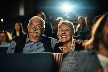 Senior couple watching a movie in the theater with popcorn