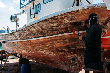 Man sanding boat in repair workshop
