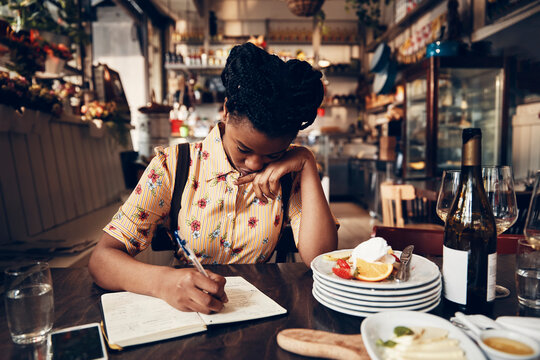 Young waitress doing expenses at a restaurant table