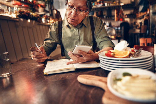 Senior waitress doing expenses at a restaurant table