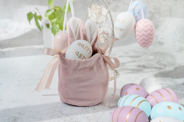 Spring Easter still life. Painted eggs in a silk decorative bag with bunny ears. Easter decor on...