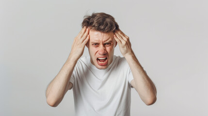 man in visible distress, with his eyes tightly shut and hands pressed against his temples, suggesting he is experiencing a severe headache or migraine.