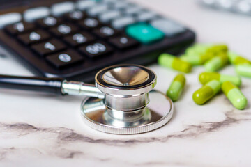 Healthcare Economics. A visual representation of the financial aspects in healthcare, featuring a calculator, stethoscope, and green capsules.