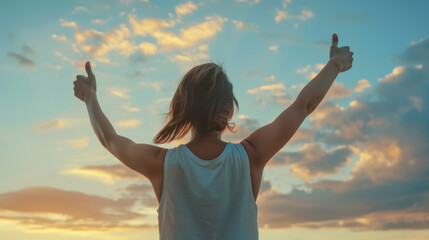 a person from behind, raising their arms with thumbs up towards the sky as the sun sets or rises, embodying a sense of accomplishment and positivity.