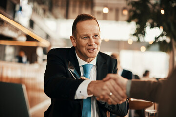 Businessmen shaking hands at an indoor cafe after making a deal