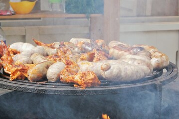 Fried sausages and chicken wings on barbecue grill in the village. Frying meat on open fire....