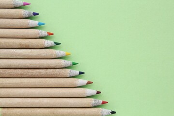 Multi colored pencils isolated on green background. Back to school concept. Sketching and drawing...