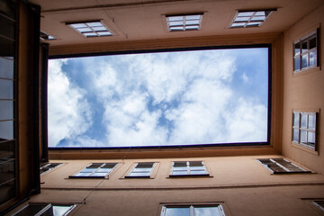 View of the sky with clouds from the closed courtyard of a residential building in the form of a...