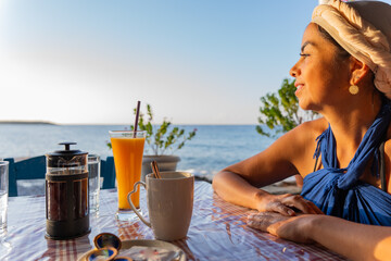 Beautiful woman in Greek outfit enjoying an excellent breakfast in a typical Greek tavern at dawn...