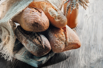 Assortment of various delicious freshly baked breads on a white wooden background. Ciabatta,...