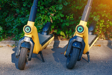 Charged electric scooters for rent stand on parking zone. Electric scooters parked in the city....