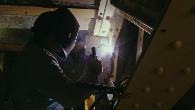 Ouvrier soudant une pi&egrave;ce m&eacute;tallique sur un chantierr industriel