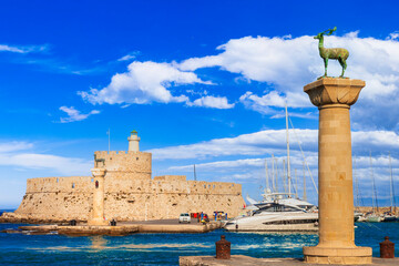 Greece travel, Dodecanese. Rhodes island. entrance of Mandraki Harbor with symbol statue of deer and old lighhouse - 746725716