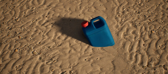 Plastic blue container with red cap lying in rippled sand of beach. - 746726109