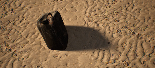 Plastic black container lying in rippled sand of beach. - 746726114