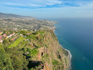 Fototapeta na wymiar Spectacular aerial view of city Funchal seen from viewing platform Cabo Girao Skywalk, Madeira island, Portugal, Europe. Majestic coastline with steep cliffs along Atlantic Ocean. Travel destination