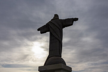Silhouette of majestic statue of Christ the King statue (Cristo Rei) in Garajau, Madeira island, Portugal, Europe. Landmark against dramatic sky. Serene tranquil atmosphere. Tourist destination