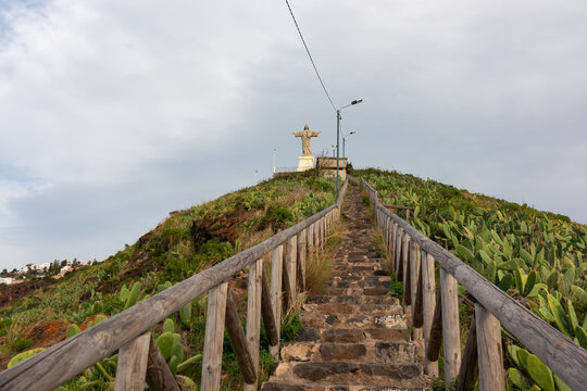 Wooden staircase to Cristo Rei statue on hilltop of Garajau, Canico, Madeira island, Portugal, Europe. Idyllic coastal hiking trail with panoramic view of tropical plants. Religious travel destination