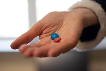 Woman's hand with red and blue candies / pills