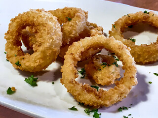 Onion rings shot up close on a white plate