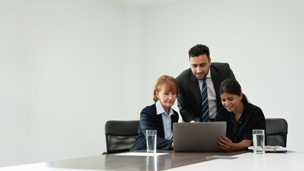 businesspeople discussing papers and working on laptops, indicating active discussion or presentation,with a laptop in the background.