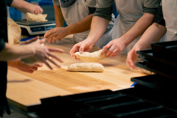 layout in a professional kitchen a group of bakers at the table process the dough and form it into mold