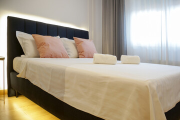 Fototapeta na wymiar Clean towels on bed in modern interior bedroom 