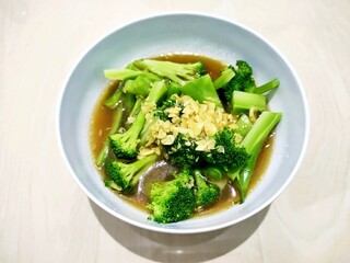 A close up view of delicious broccoli with soy sauce and garlic in a white bowl