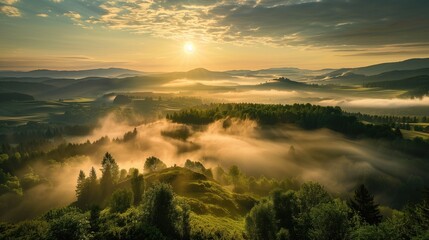 Beautiful sunset or sunrise view with sun rays in the mountains or hills with amazing misty foggy green valley with creeping fog from above