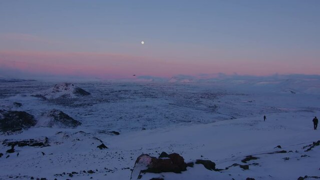 Man and woman hiking up Helgafell mountain Iceland under full moon