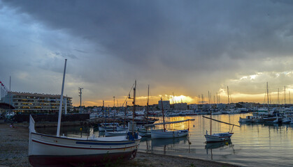 Sunset on the beach with fishing boats and cloudy sky
