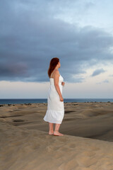 Young woman stands with her back in the sand dunes