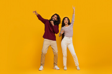 Carefree young indian man and woman have fun on yellow