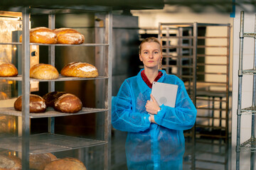 in a professional kitchen a young woman in a blue robe creates a report on production and quality