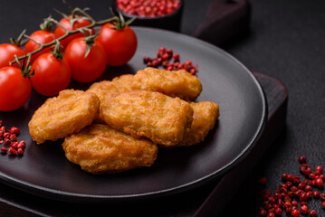 Delicious fresh crispy chicken nuggets on a dark concrete background