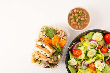 Grilled chicken in a food box with salad and rice sprinkled with sesame seeds aerial top view