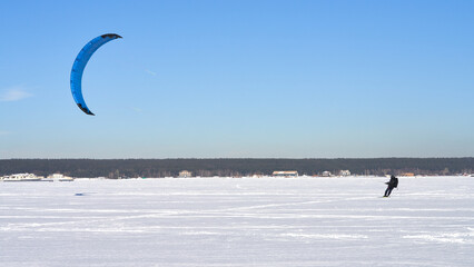 A lone skier rides a kite on a snowy frozen body of water. Copy space.