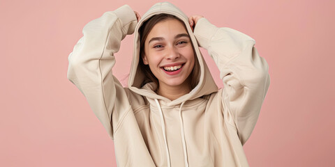 E-commerce photography of a happy woman model wearing a light tan hoodie, solid color background, hands slightly out of scene, focal point is the front of the hoodie