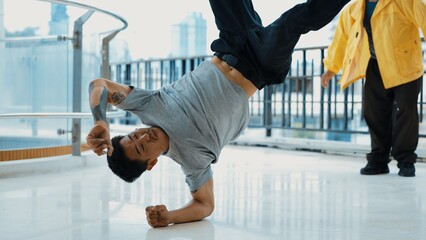 Caucasian hipster doing head spin while surrounded by multicultural friends. Hip-hop dancer practicing break dancing or preparing for street dancing. B-boy dance concept. Outdoor sport 2024. Endeavor.