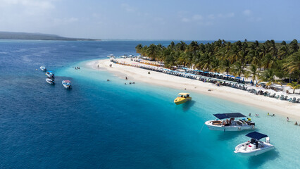 View of a small cay of white sands and deep blue waters with some boats around
