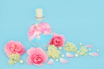 Rosewater for natural skincare with rose and elder flower flowers, heart shaped bottle on blue. Balances skin ph and oils, reduces redness, naturally hydrates and firms skin.