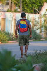 A man walking with a tri-colored backpack