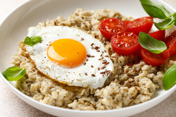 Oatmeal with fried sunny-side-up egg, tomatoes and basil