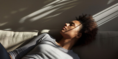 Obraz premium Lifestyle portrait of black woman napping on couch in sunlight