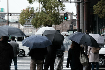 雨降りの日横断歩道で信号待ちする人々。冬の日大阪梅田駅前で撮影。