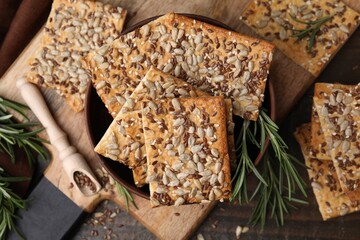 Cereal crackers with flax, sunflower, sesame seeds and rosemary on wooden table, top view