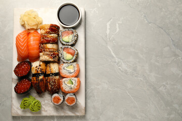 Set of tasty sushi rolls on light grey marble table, top view. Space for text