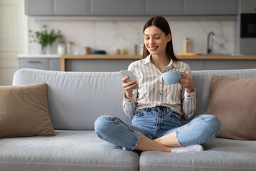 Relaxed woman with coffee and smartphone on couch