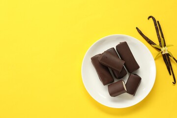 Glazed curd cheese bars, vanilla pods and flower on yellow background, top view. Space for text